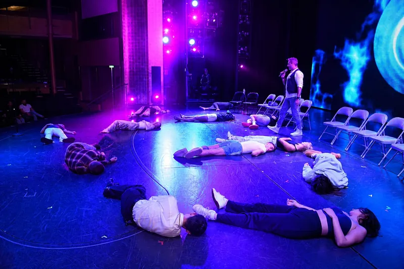 Hypnotised volunteers lying across a cruise theatre stage under blue light